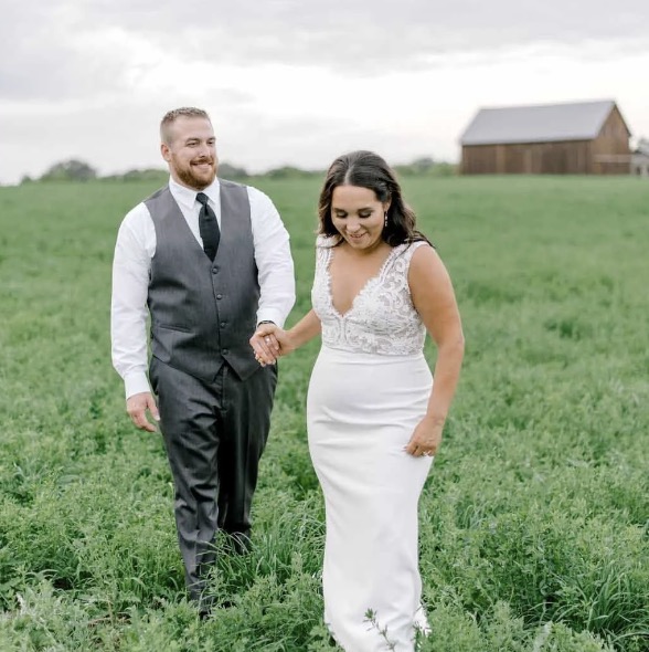 bridge and groom after the ceremony in the field with barn in background
